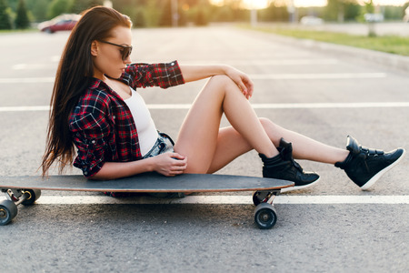 Beautiful and sexy girl sitting on the skateboard