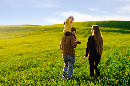 Happy and young parents with a young son walking on a field at sunset in the summer. Concept of familyの写真素材