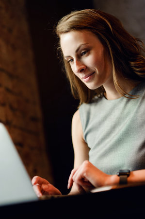 Young girl working at her laptop by the windowの写真素材