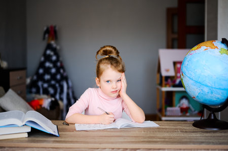 Back to School. Kid doing homework, sitting on the table, reading books near globe. Distance education conceptの写真素材