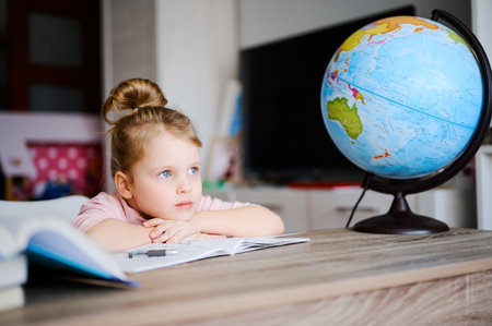 Cute little caucasian preschool girl doing homework. Child reading books and learning at home. Distance educationの写真素材