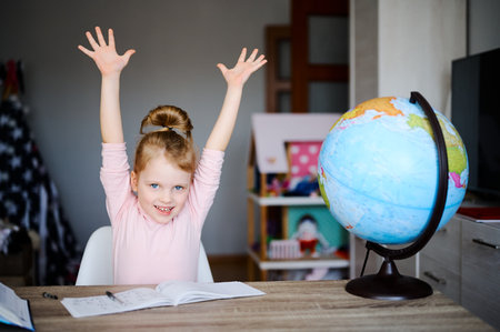 Little caucasian schoolgirl smiling, raised her hands up, reading books, doing homework. Training...