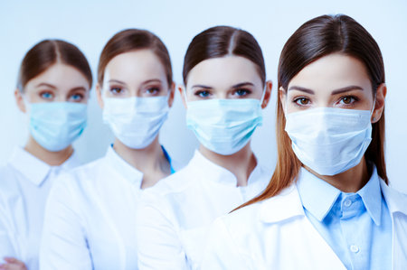 Masked young female doctor on an isolated white backgroundの写真素材