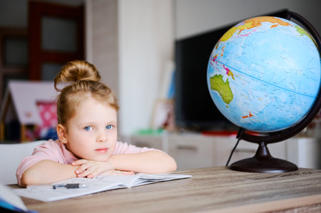 Cute little caucasian preschool girl doing homework. Child reading books and learning at home. Distance educationの写真素材