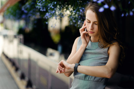 Businesswoman talking on smartphone and chek smart watches on the street