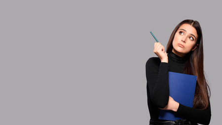 Thoughtful concentrated busy woman holds pencil and notepad, female student with an exercise book and pen, isolated backgroundの写真素材