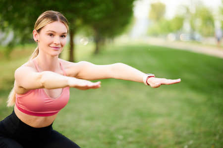 Squats. Sports Woman In fitness clothes squatting. Burn in buttocks. Side view of young woman in sportswear doing squatの写真素材