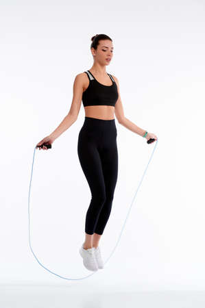 Spotrswoman jumping with rope on white isolate background. Fitness female doing physical exercise. Healthcare and weightlose conceptの写真素材