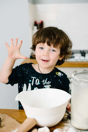 Little boy in the kitchen helping to cook the dough for bakingの写真素材