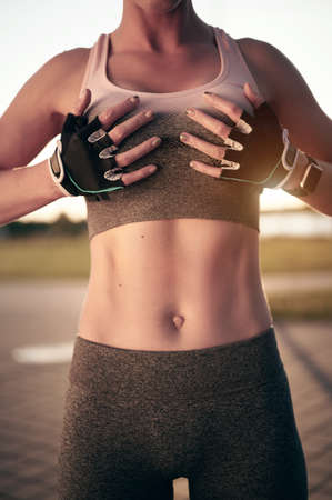 Fit woman with sporty body and strong abs outdoor, showing flat belly, abs, abdominalsの写真素材