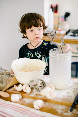 Little boy in the kitchen helping to cook the dough for bakingの写真素材