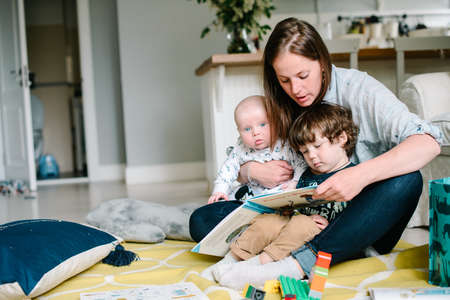 Mother reading book with children sitting on the floor
