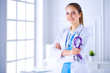 Female doctor holding stethoscope on white background in medical officeの写真素材