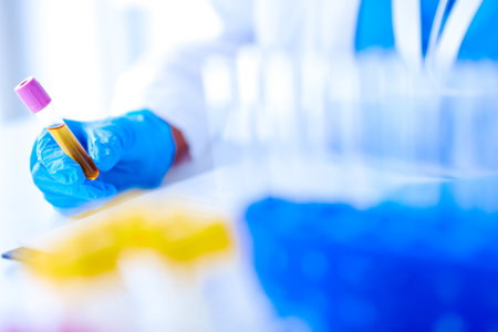 Scientist in a laboratory holds a test tube. Researcher is surrounded by medical vials and flasksの写真素材