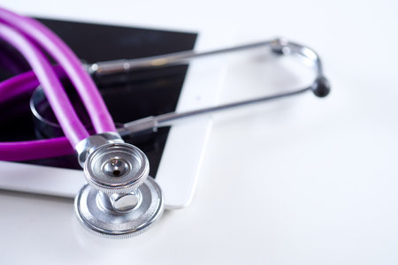Medical equipment: purple stethoscope and tablet on white backgroundの写真素材