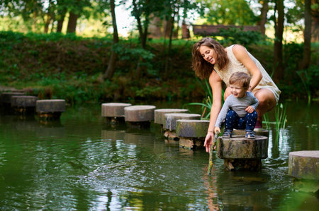 A young and pregnant mother and son walking in the park near the river in summerの写真素材