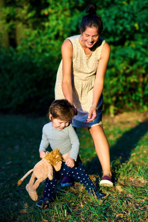 Young pregnant mother walking with her little son in summer park
