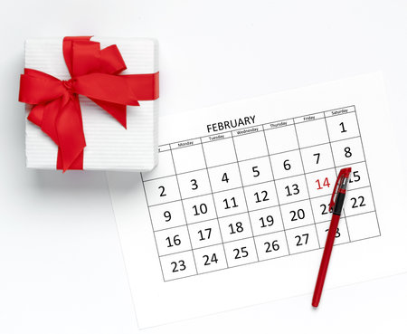 Valentine's day concept. Calendar template with pen and gift box on white background. Flat lay, mockup, top viewの写真素材
