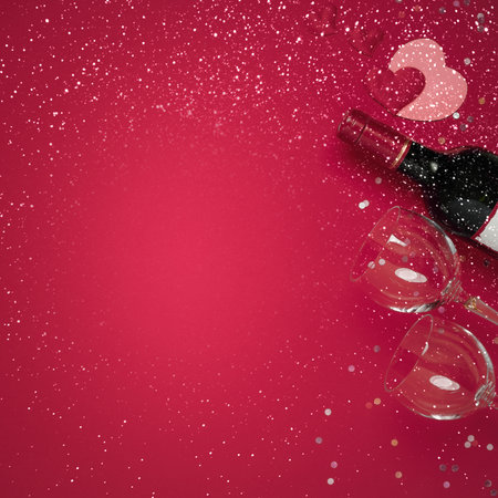 Valentines day template flat lay. Wine bottle, glasses, flowers roses with gift box on red backgroundの写真素材