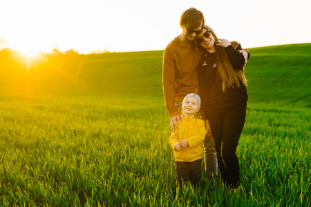 Happy family with son outdoors. Young parents walk with kid on summer field