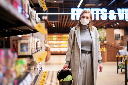 Woman in medical masks is shopping in grocery store during virus pandemicの写真素材