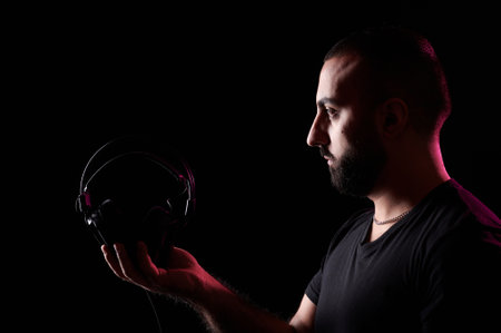 Young bearded Arab DJ musician holds headphones in his hands. International DJ Day