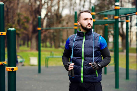 Young strong man with a rope on a sports field in the summerの写真素材