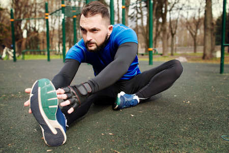 Young strong man stretches his muscles before trainingの写真素材