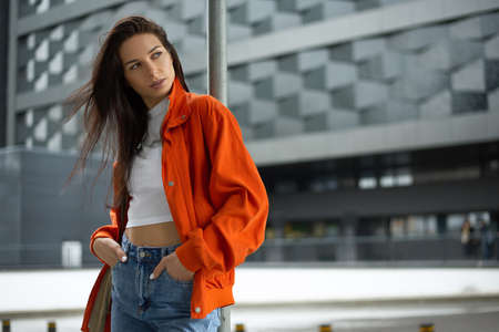Young fashionable teenager girl walks around the city in the summer in a fashionable jacket and jeansの写真素材