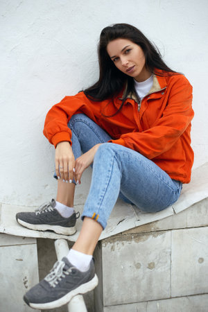 Portrait of young beautiful fashionable female hipster in red summer jacket near white wallの写真素材