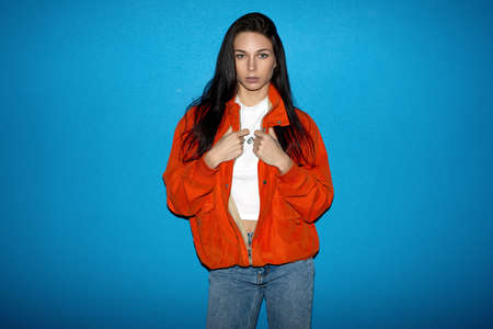 Young fashionable teenager woman near the blue wall