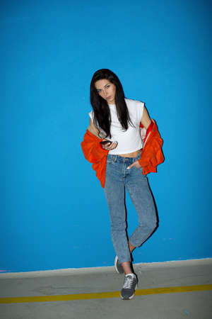 Young fashionable teenager woman near the blue wall