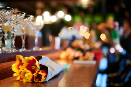 Bouquet of yellow tulips on the bar among the glasses of the restaurantの写真素材