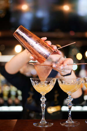 The barman makes an alcoholic cocktail and spills it through a strainerの写真素材