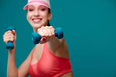Smiling attractive caucasian sporty woman with athletic strong body do exercise with dumbbells...