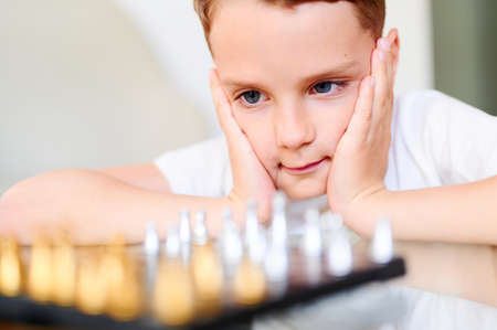Concentrated Boy playing chess at home. School kid and board gameの写真素材