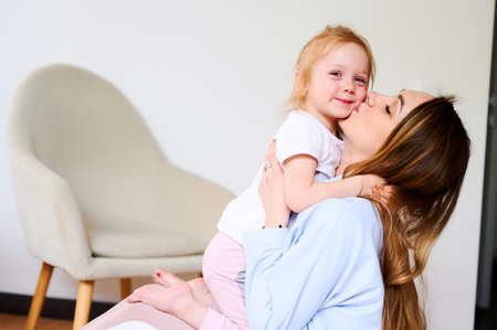 Little cute girl hugs with her mom at home. Good relationship with parents. Single motherの写真素材