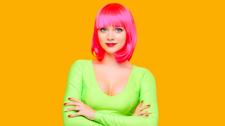 Young attractive sexy charming woman in pink wig posing on yellow backgroundの写真素材