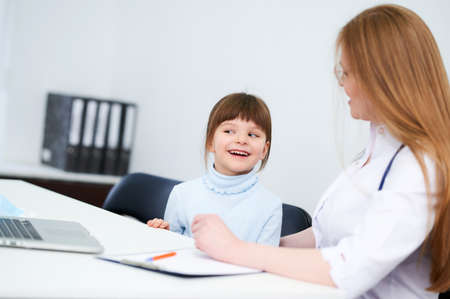 Female caucasian doctor examining little girl in officeの写真素材