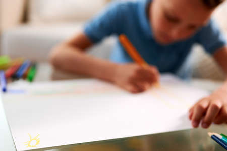Selective focus. Little schoolboy drawing picture. Back to school. Home schooling and education at...