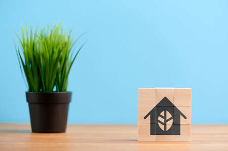 Ecology concept, wooden blocks with icon of building eco environment conservation house residential home, on blue backgroundの写真素材