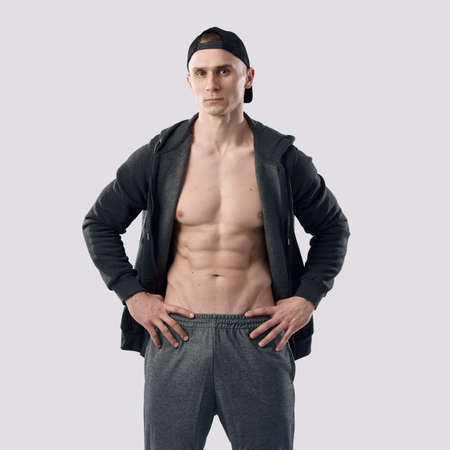 Handsome guy with strong muscular body gym trainer looking at camera on gray isolated background