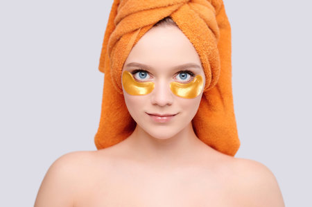 Beauty and health concept young beautiful woman with a towel on her head and patches under her eyesの写真素材