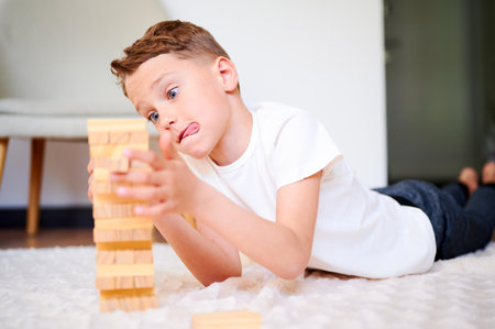 Boy playing wooden block removal tower game at home. Board game. Kids leisure concept.の写真素材