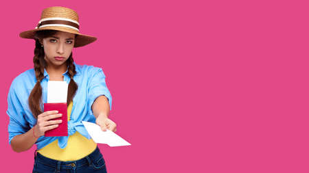 Young upset woman tourist with passport giving flight ticket. Caucasian traveler in summer casual...