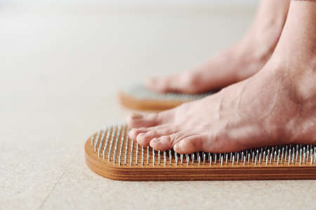 Healthy lifestile, Woman legs standing on wooden yoga Sadhu Board with nails for practice and meditation. Alternative medicine acupressure, recovery strengthの写真素材