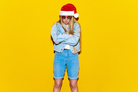 Disappointed Christmas woman in Santa Claus hat on yellow isolated background. Upset female complaining and arguing, talking troubled uneasyの写真素材
