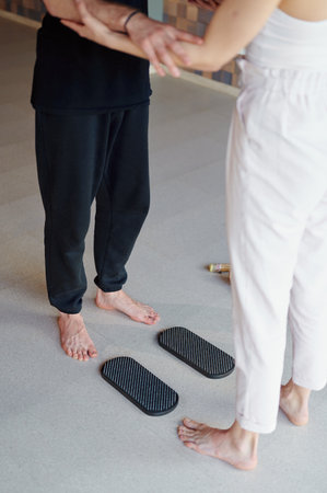 Practice of standing on nails. Woman helps man stand on sadhu board with nails in yoga studio.の写真素材
