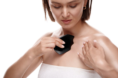 Beautiful naked woman facial jade gua sha isolated on white. Female massaging face by guasha stone scraper for skincare, daily beauty treatment.の写真素材