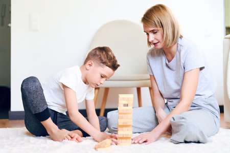 Cute little caucasian boy and his mother play board game on the floor at homeの写真素材